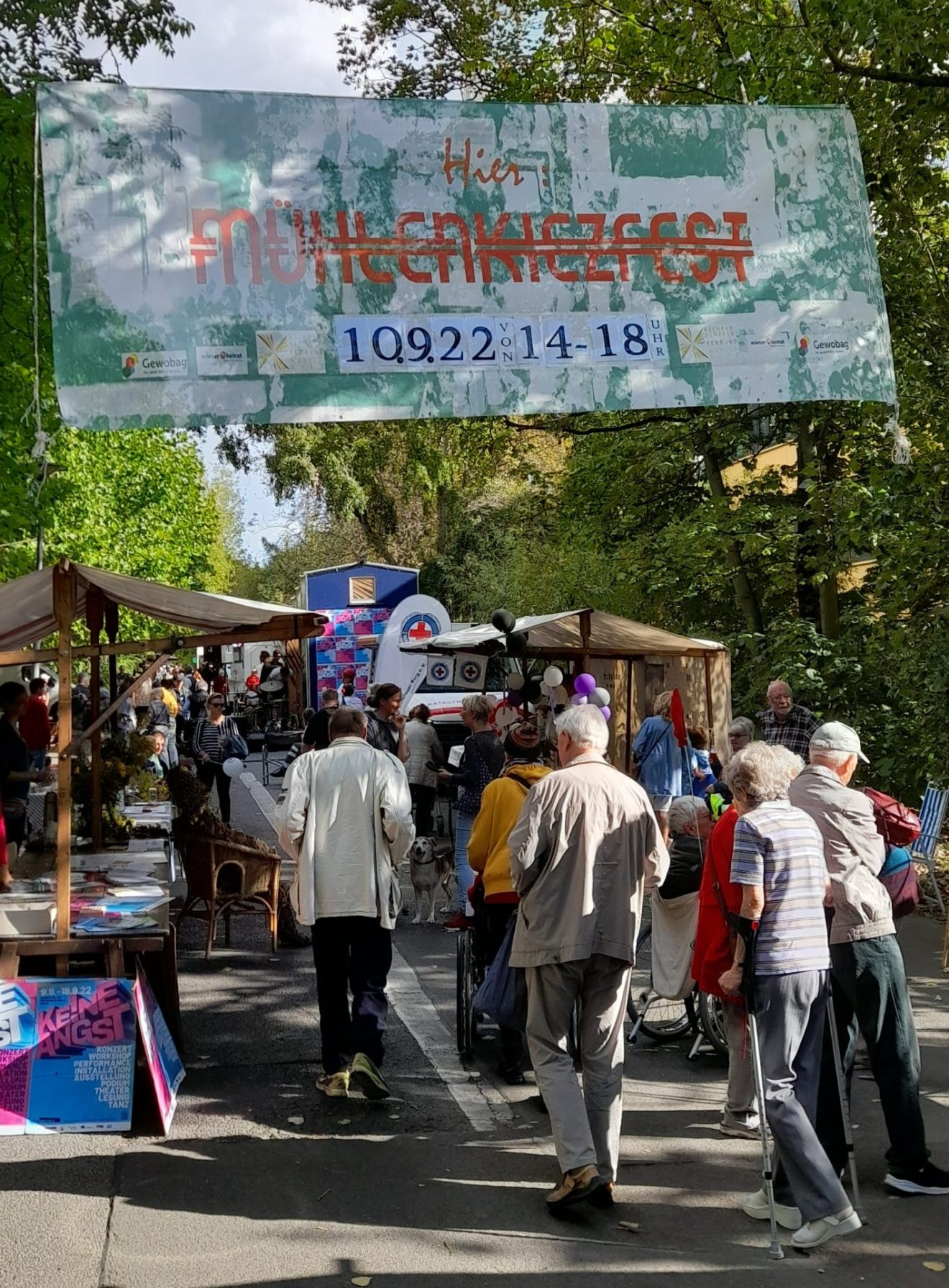 Blick auf die Fußgängerpromenade: Menschen, Stände und Plakate auf dem Mühlenkiezfest